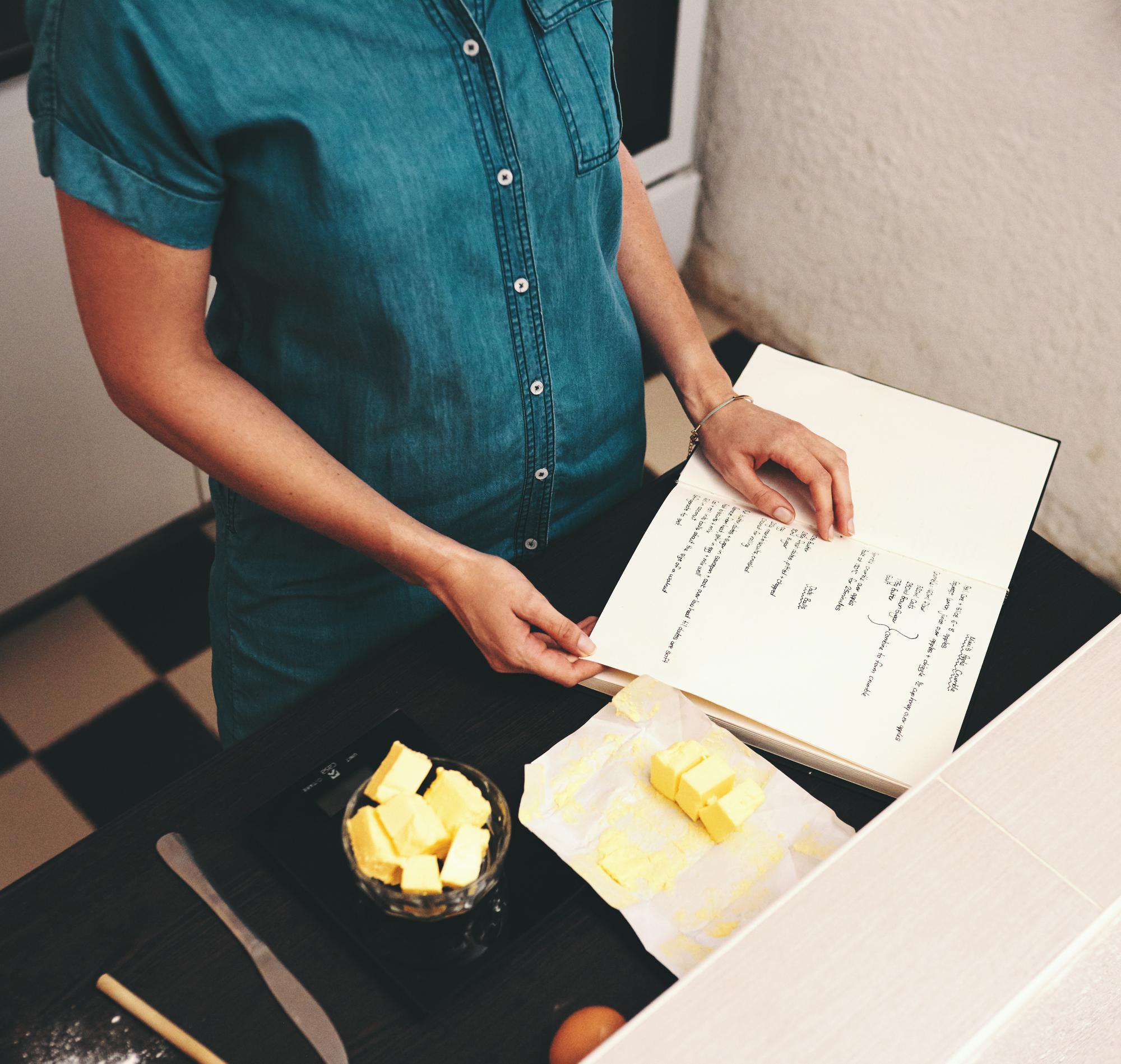 Köchin schreibt Rezeptnoten in Notizbuch